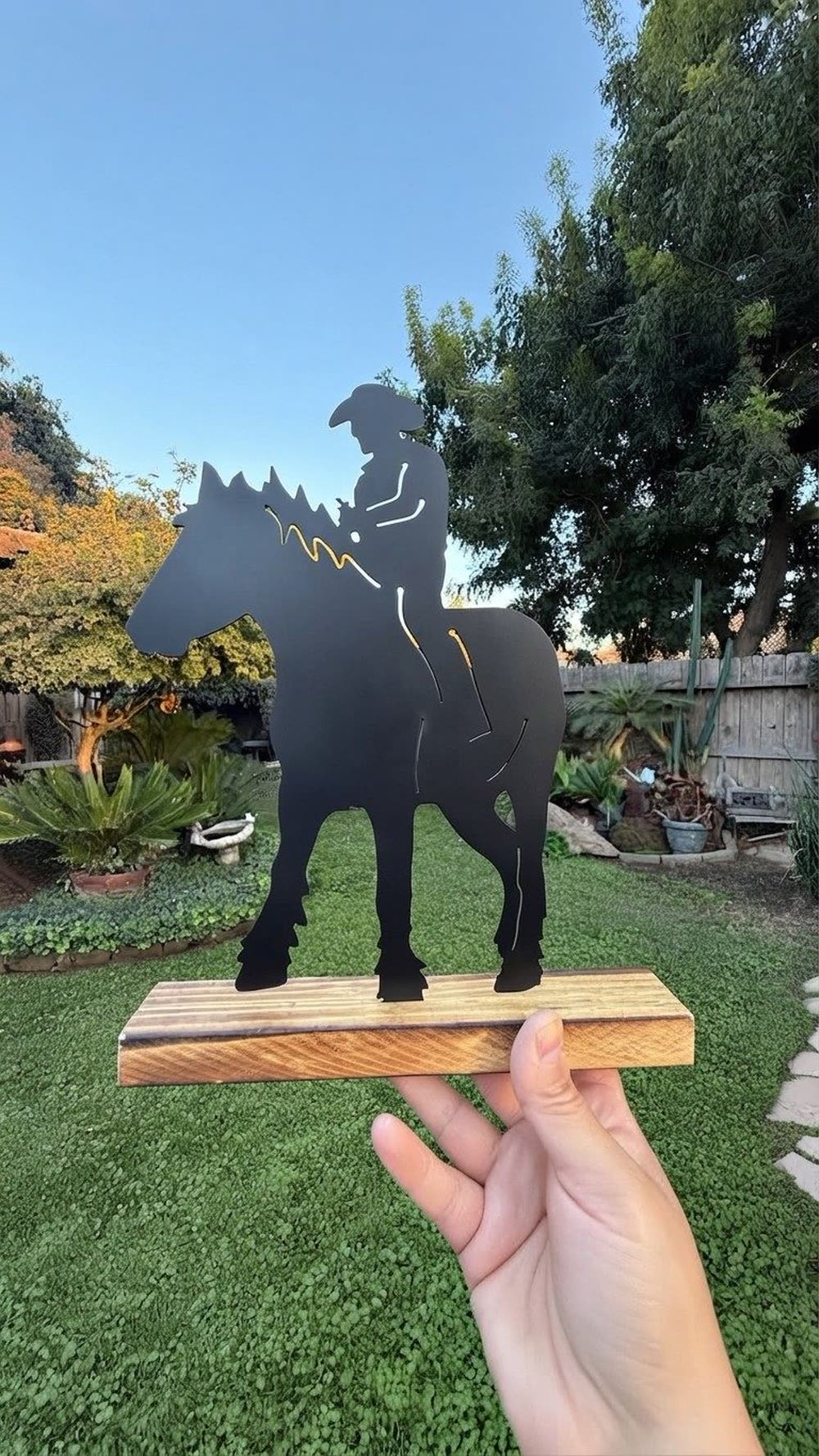 A steel silhouette of a cowboy on horseback, on a wood base.