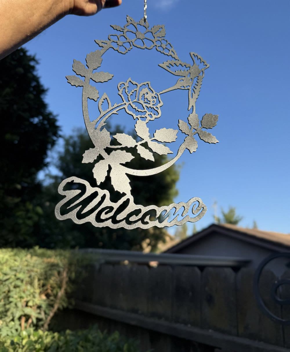 A steel wreath of roses above the word Welcome in script.