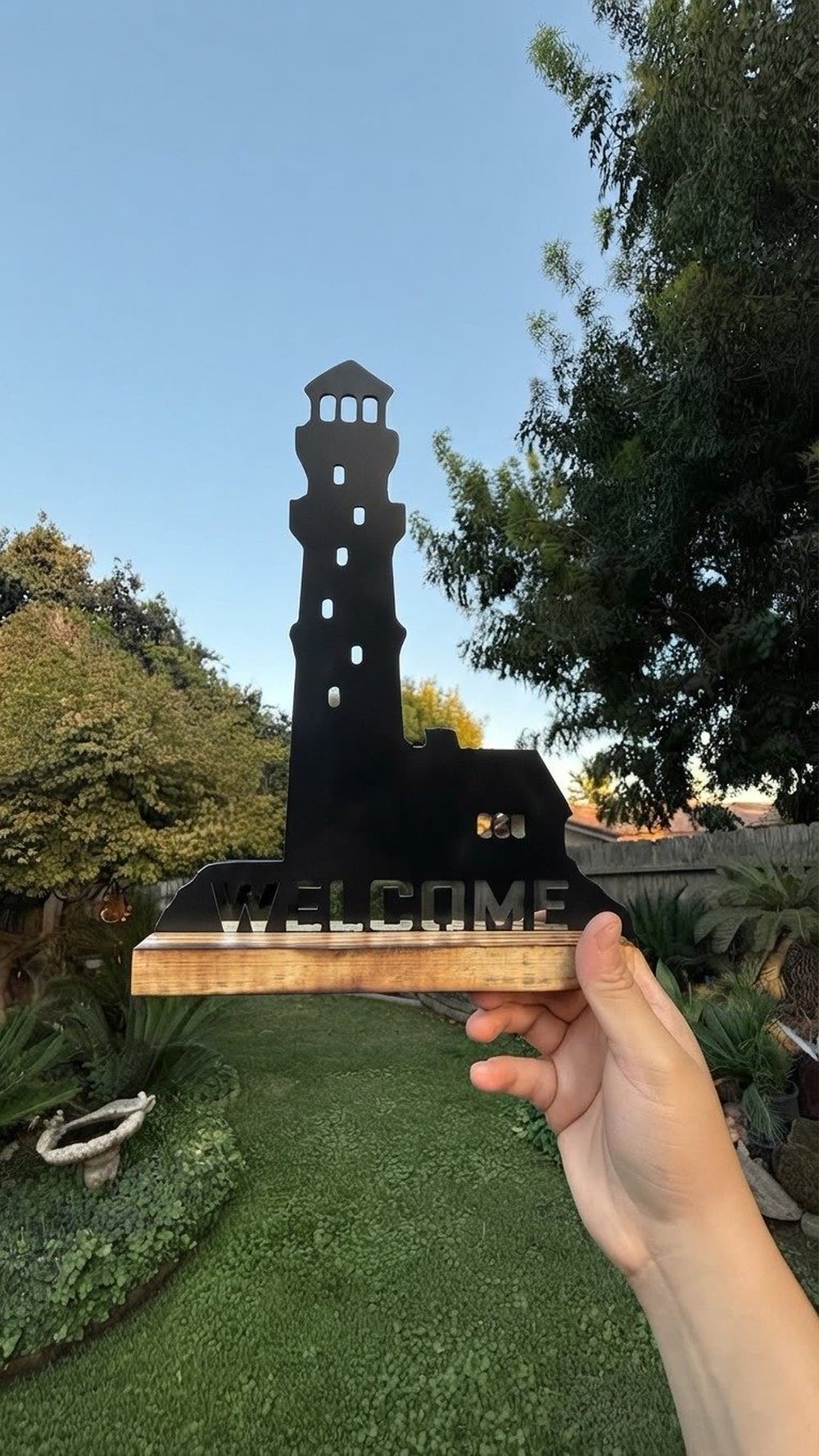 A steel Welcome sign with a lighthouse, on a wood base.