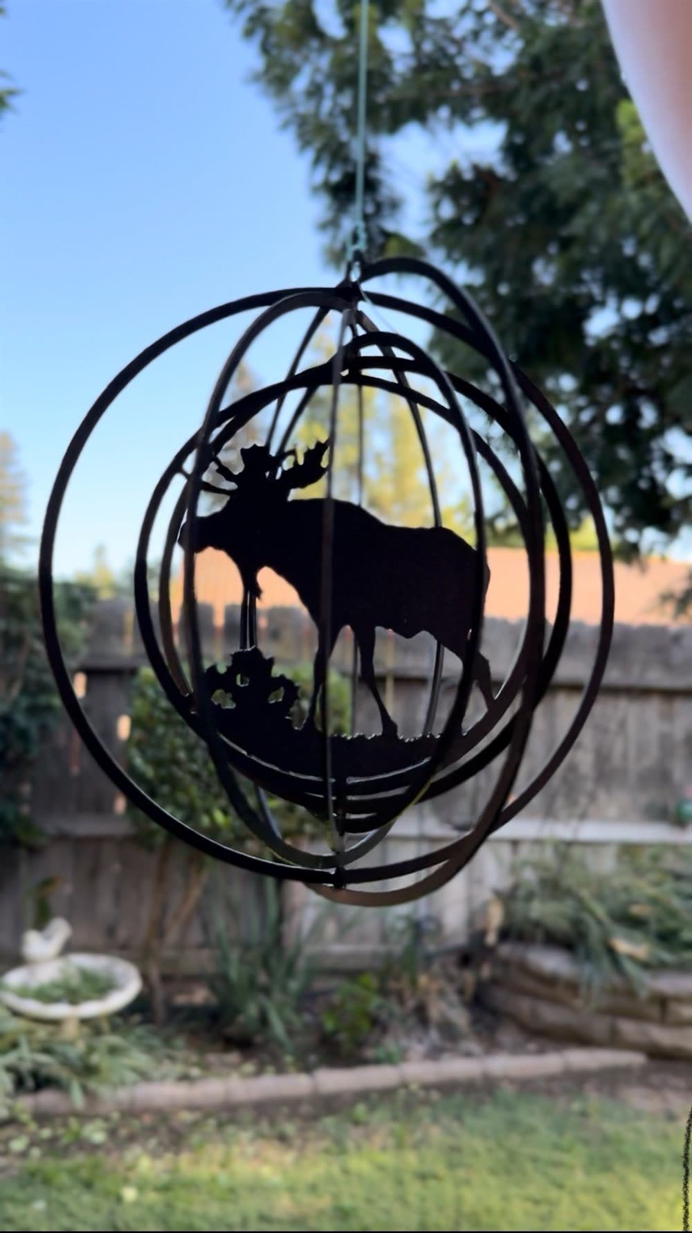 A steel moose wind spinner inside a spinning metal sphere.